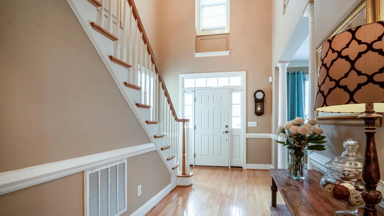 Pasillos con encanto: escalera de madera, puerta blanca y un jarrón con rosas.