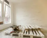 Herramientas listas para como pintar un palet. Madera blanca apilada, sierra ingletadora y pared con ladrillos blancos.