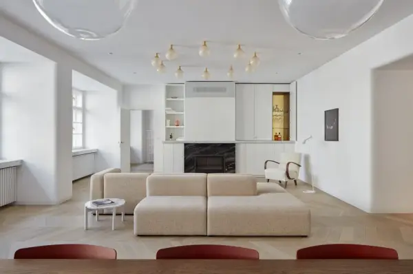Un moderno sofá en medio del salón, con chimenea y estanterías integradas.